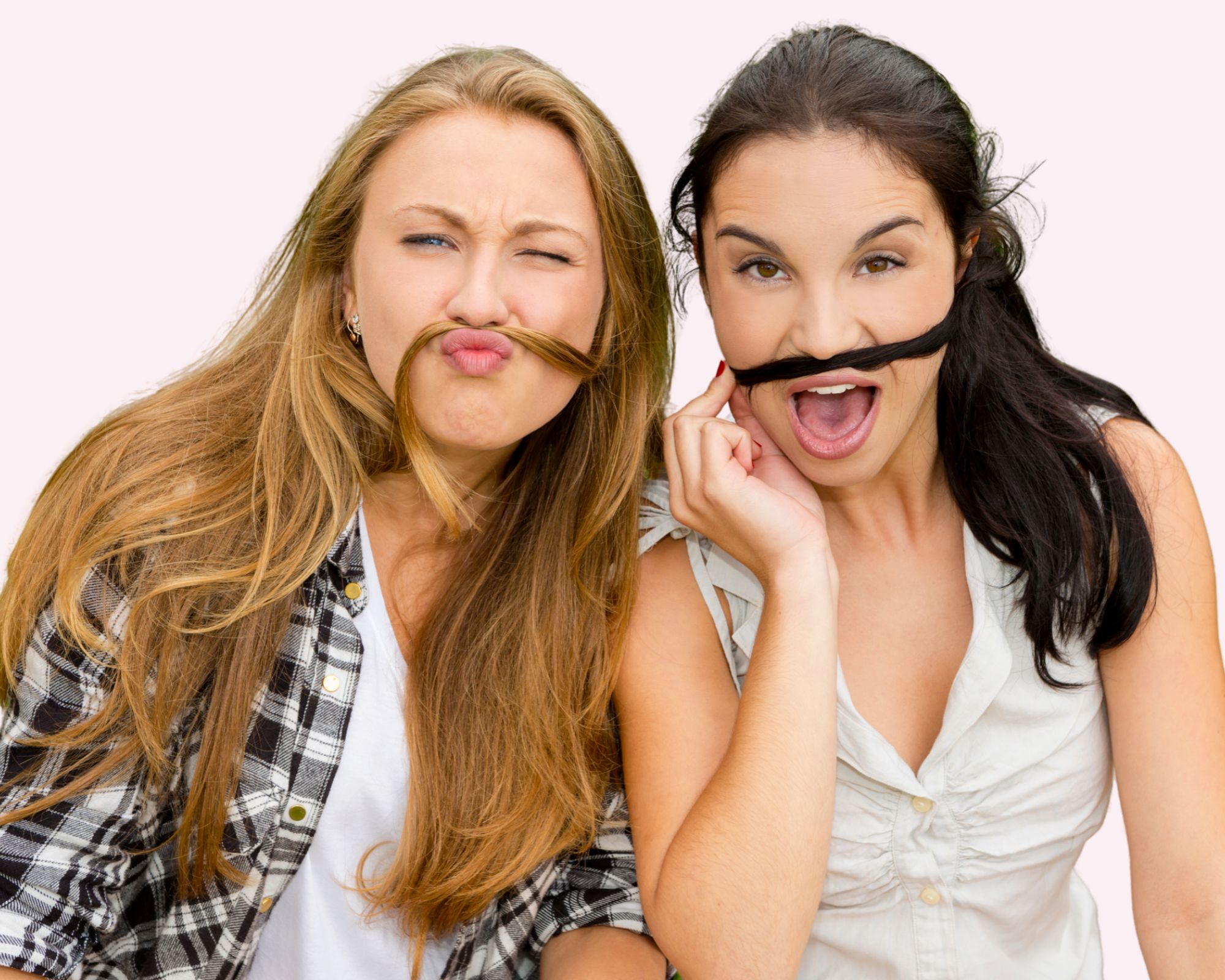 Two friends being silly, holding strands of their hair up as mustaches